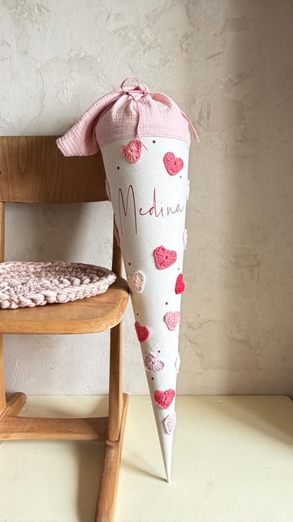 Personalisierte Herz-Schultüte in Rot, Rosé und Pink am Holzstuhl